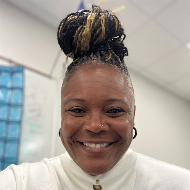 Iyhia McMichael, the first Black softball player inducted into the Mississippi State Hall of Fame, smiles during a classroom break at Emerson High School in Frisco, Texas, where she teaches and coaches softball.
