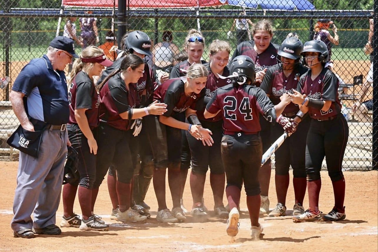 Gabby Bonilla is greeted at home plate by her teammates after a home run during travel ball action. Her energy and team-first mentality are hallmarks of her game.